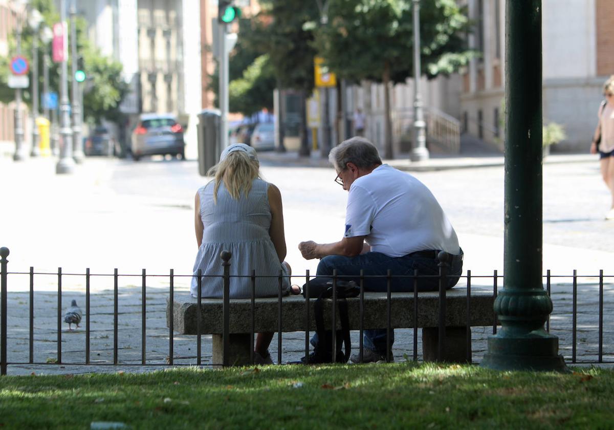 Dos personas, sentadas en un banco en Valladolid, en una imagen de archivo.