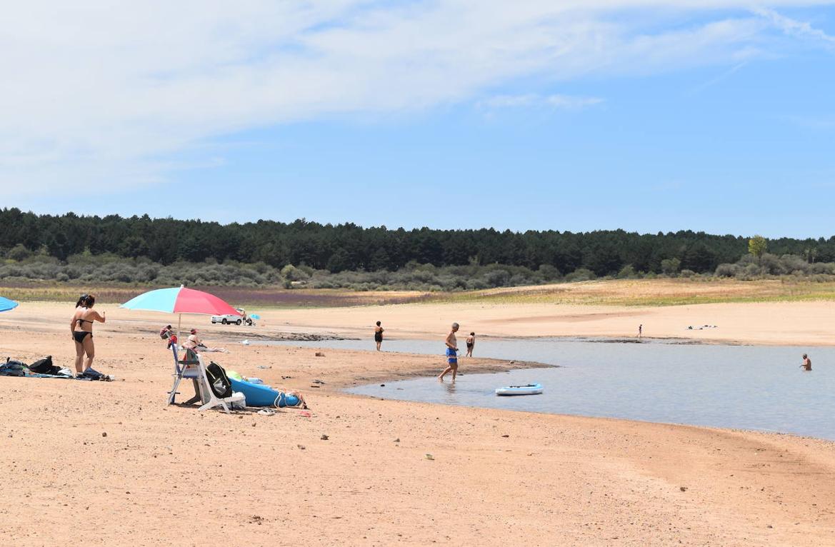 Sombrillas, toallas extendidas y bañistas en el pantano de Aguilar.