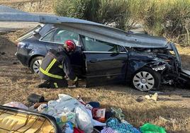 Un bombero realiza trabajos en el vehículo accidentado, sobre el que aún se encuentra el quitamiedos.