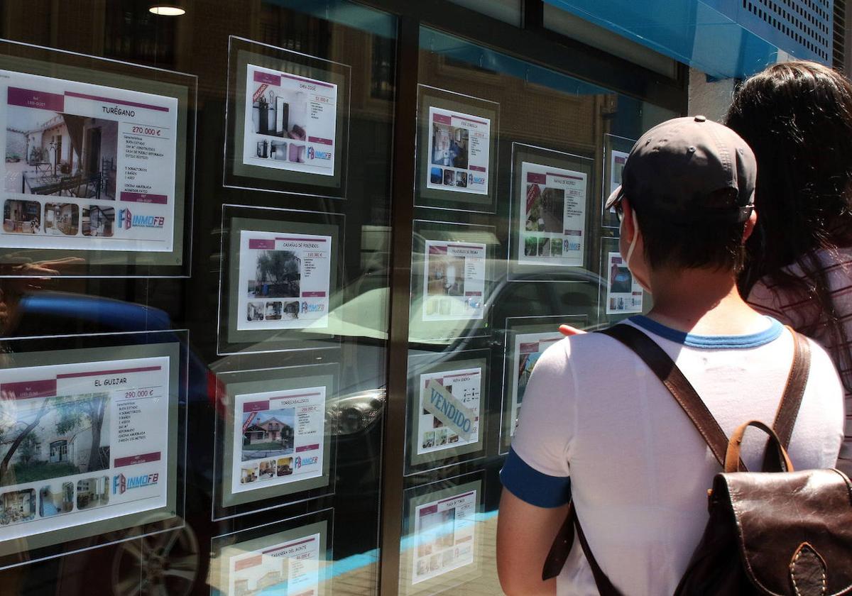 Un joven observa anuncios de casas en venta en una inmobiliaria.