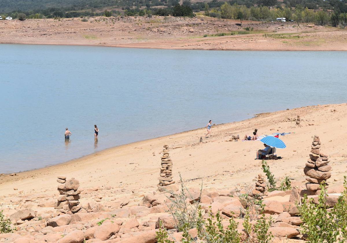 Varias personas toman el sol y se bañan, este pasado puente en el pantano de Aguilar.