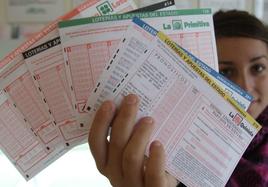 Una joven muestra boletos de lotería y quinielas en una administración, en una imagen de archivo.