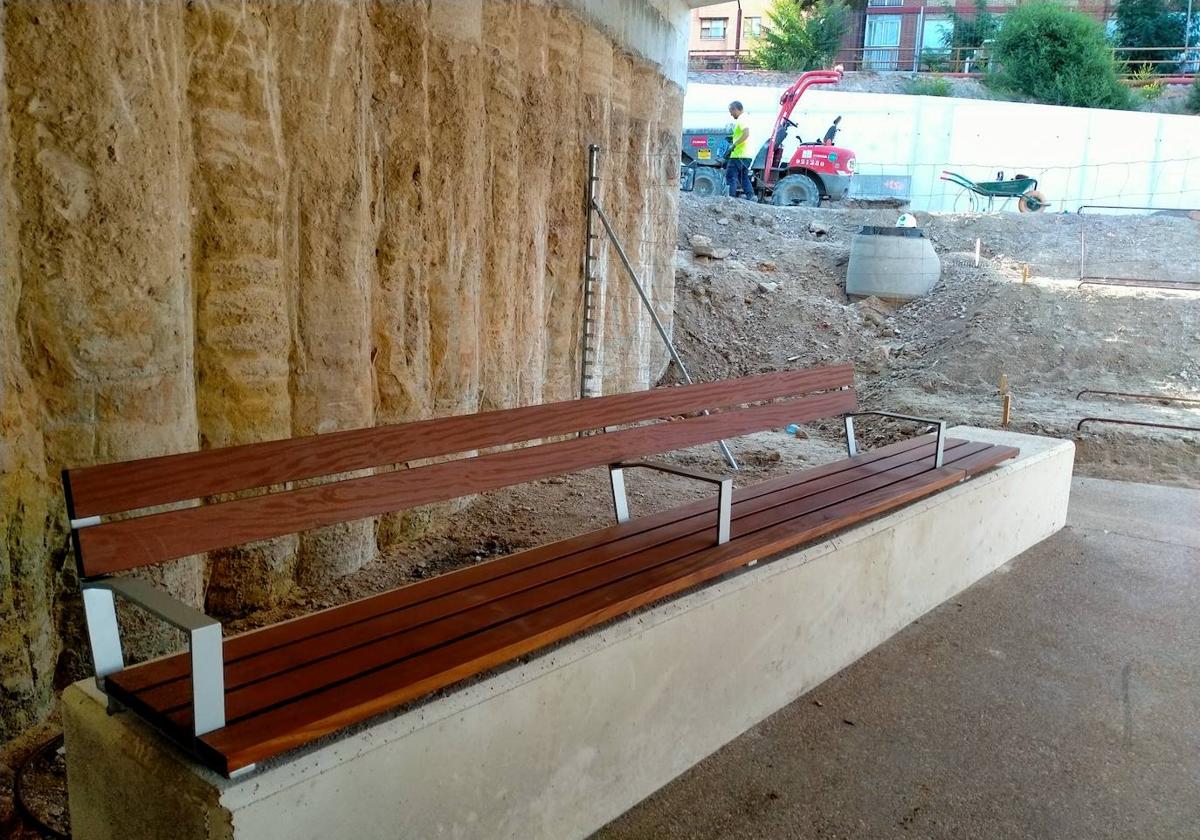 Uno de los bancos de madera instalados en el paso de Panaderos, al fondo con las obras del túnel de Labradores.