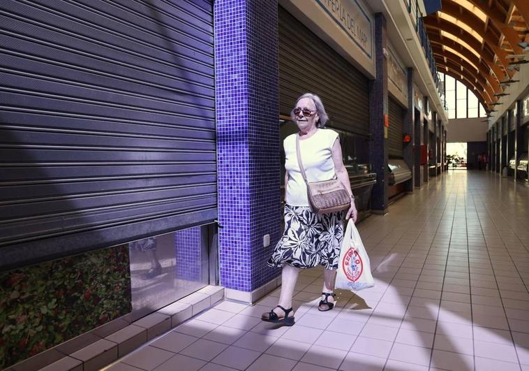 Una mujer camina entre un pasillo de tiendas cerradas en el mercado de Las Delicias.