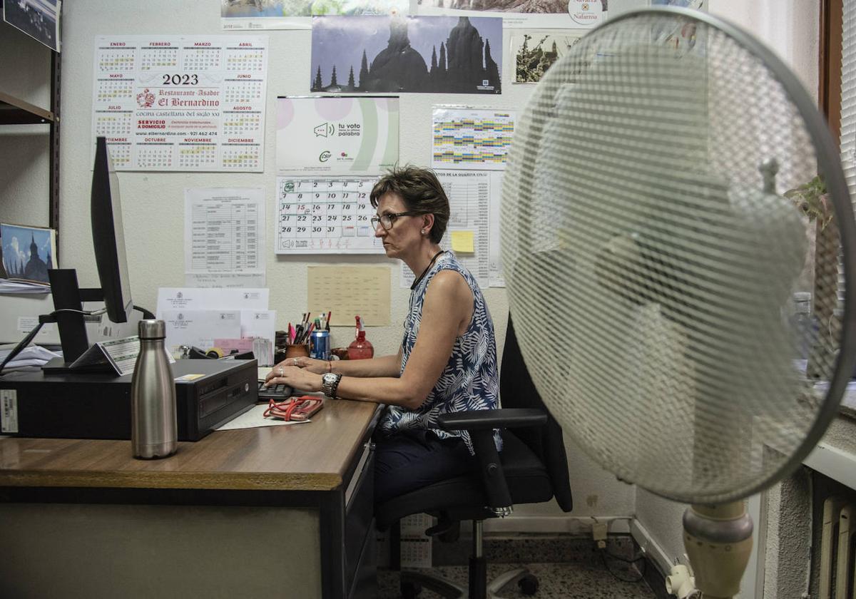 Funcionaria de justicia trabaja delante de un ventilador para combatir el calor.