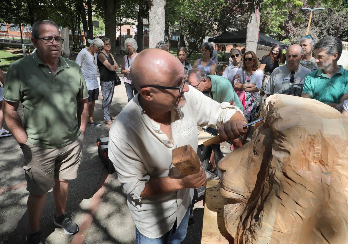 El escultor Alfredo Martín 'Chis' talla la cabeza de un león ante la mirada del público.