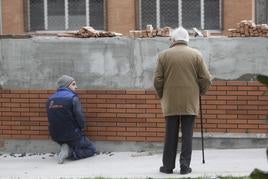 Un jubilado observa el trabajo de un albañil.