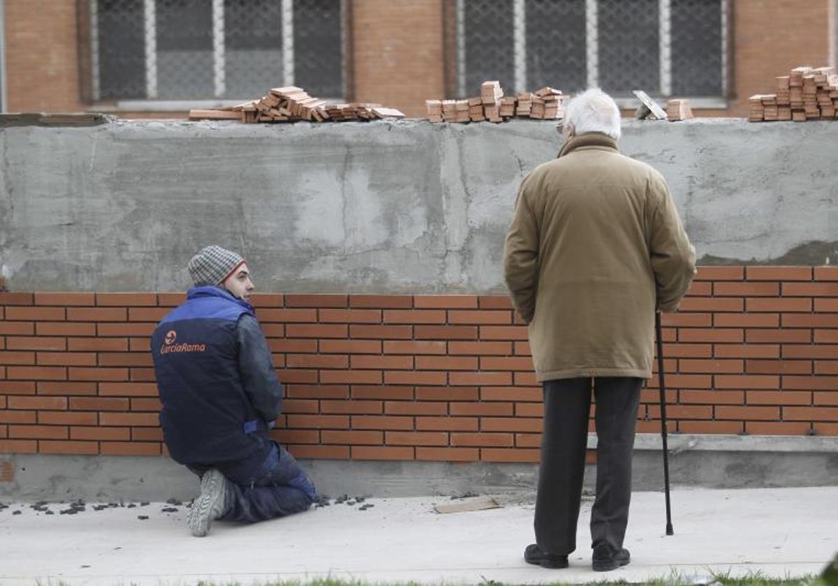 Un jubilado observa el trabajo de un albañil.