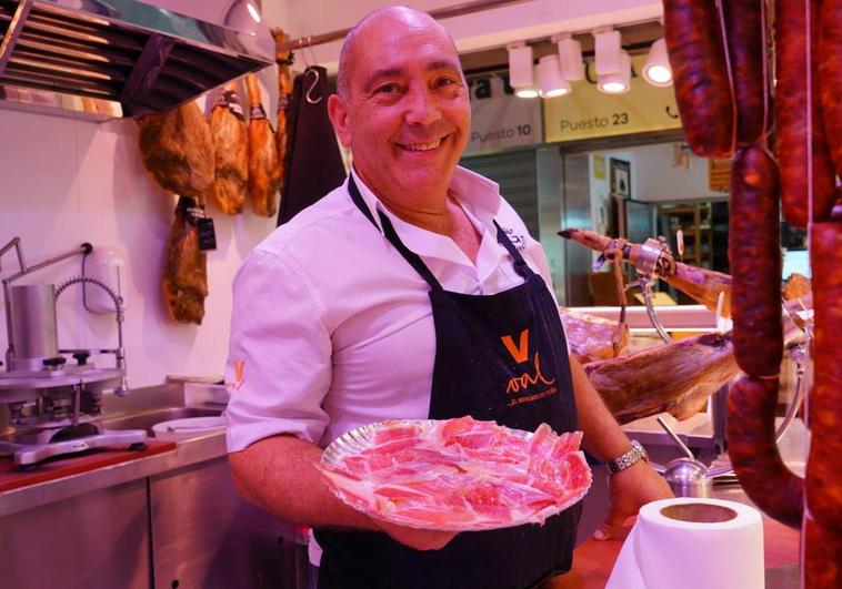 Felipe González muestra en su charcutería un plato con trozos de jamón ibérico.