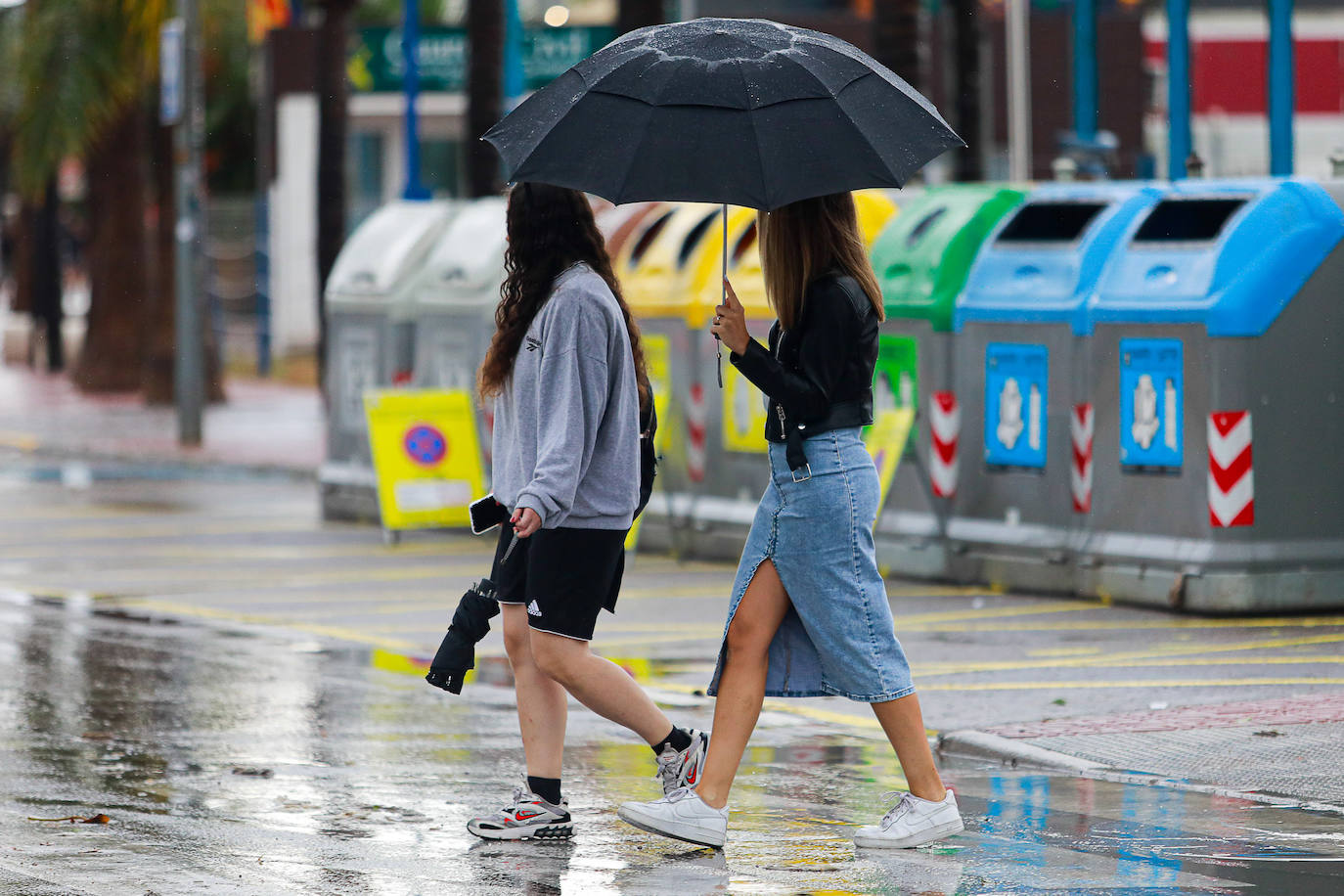 Dos chicas caminan por la calle bajo un paraguas.