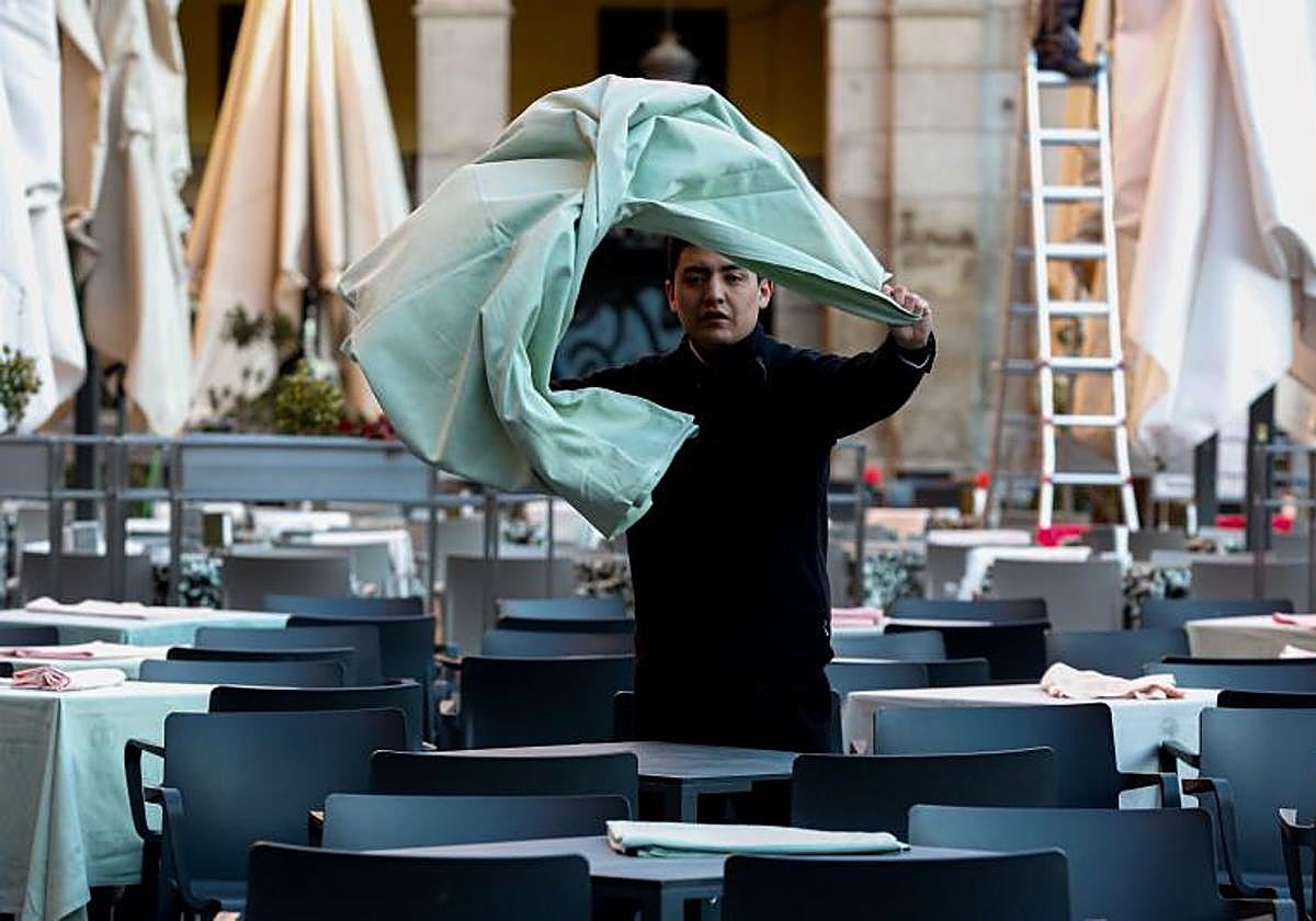 Un camarero prepara las mesas de una terraza.