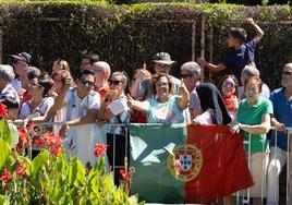 Aficionados posan con las banderas de Argentina y Portugal en las vallas de la línea de salida.