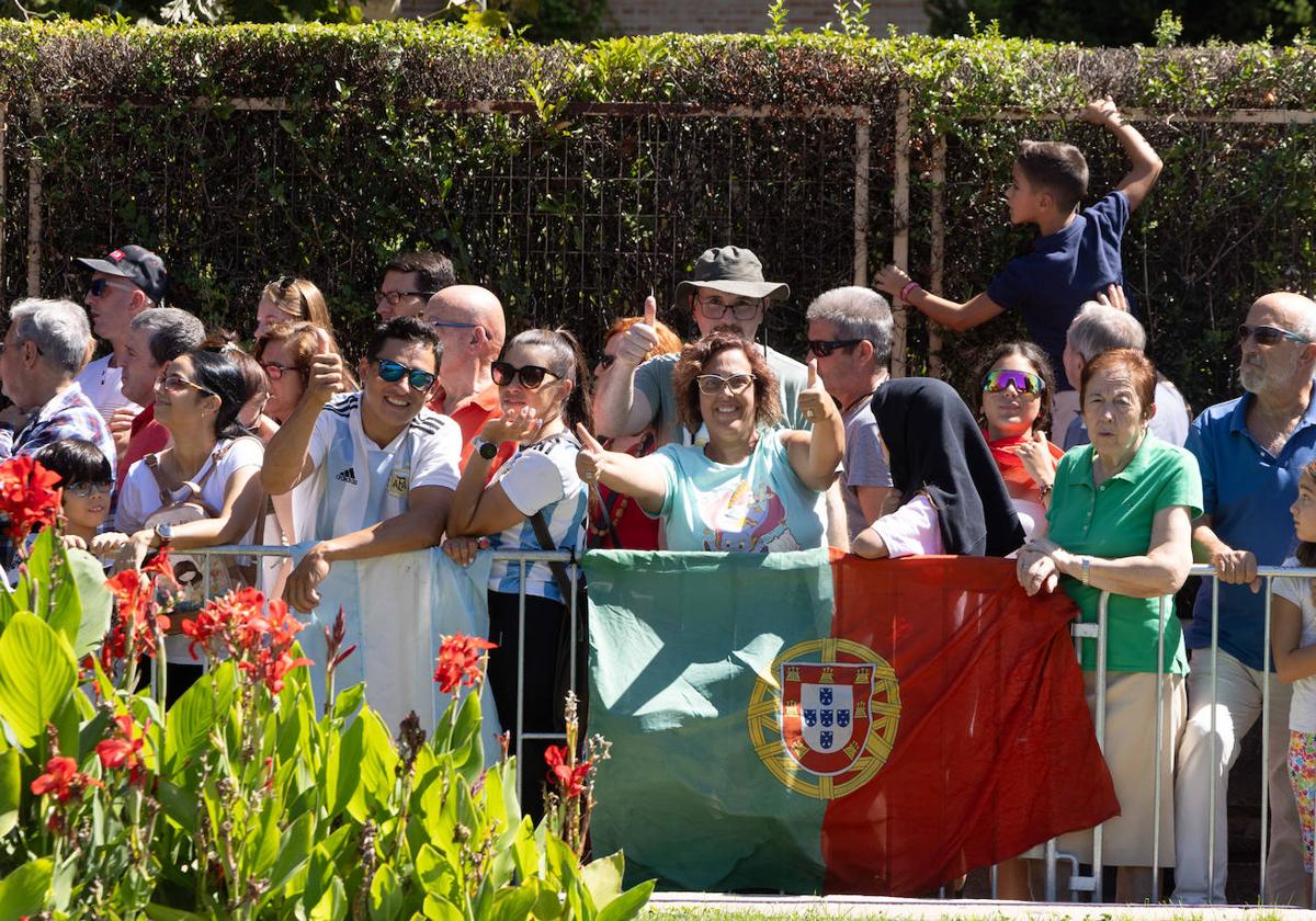 Aficionados posan con las banderas de Argentina y Portugal en las vallas de la línea de salida.