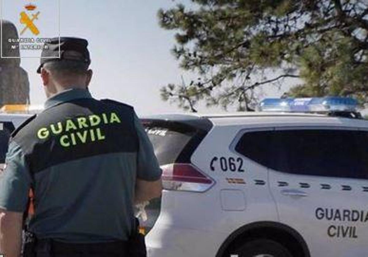 Un agente de la Guardia Civil junto a un coche patrulla.