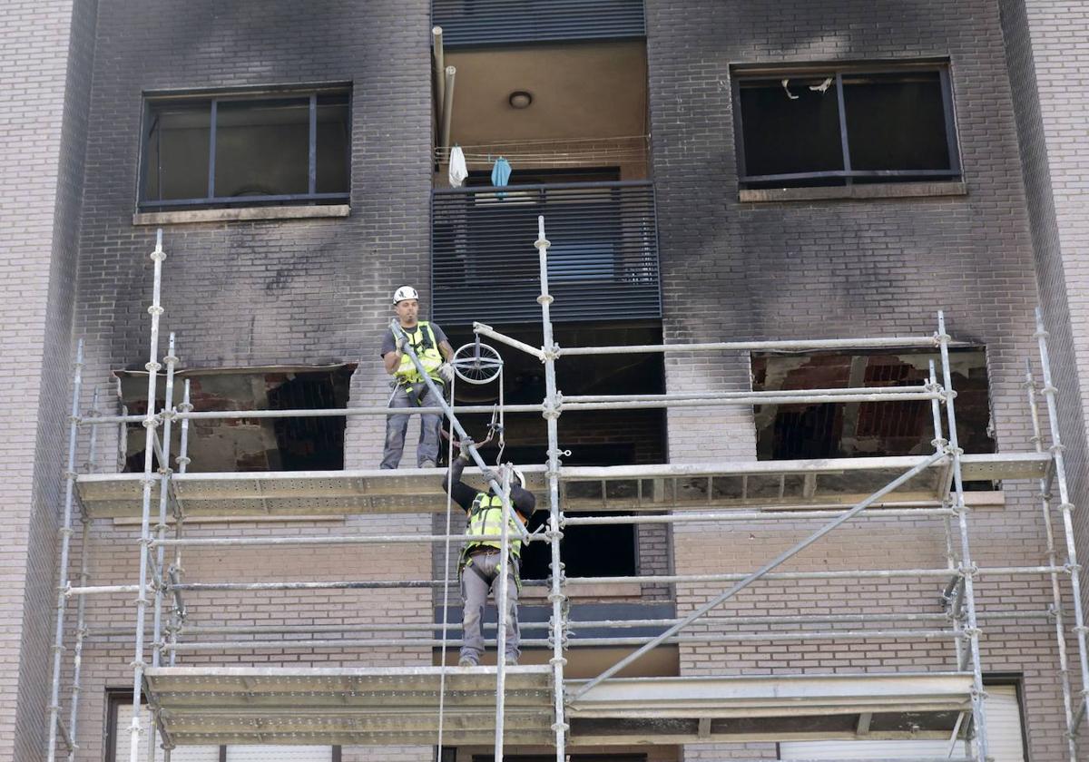 Dos operarios instalan la semana pasada un andamio frente a la fachada del edificio afectado.