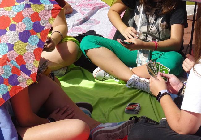 Un corrillo jugando al 'UNO' ante el escenario de la Plaza Mayor.