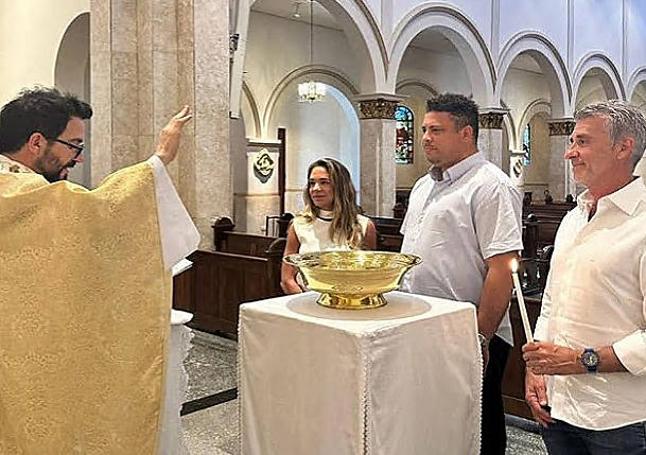 El párroco Don Oswaldo oficia el bautismo de Ronaldo, junto a sus padrinos, Malu y Amilcar.