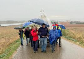 Los fieles, protegidos con paraguas, trasladan hasta el santuario a la Virgen, cubierta con un plástico.