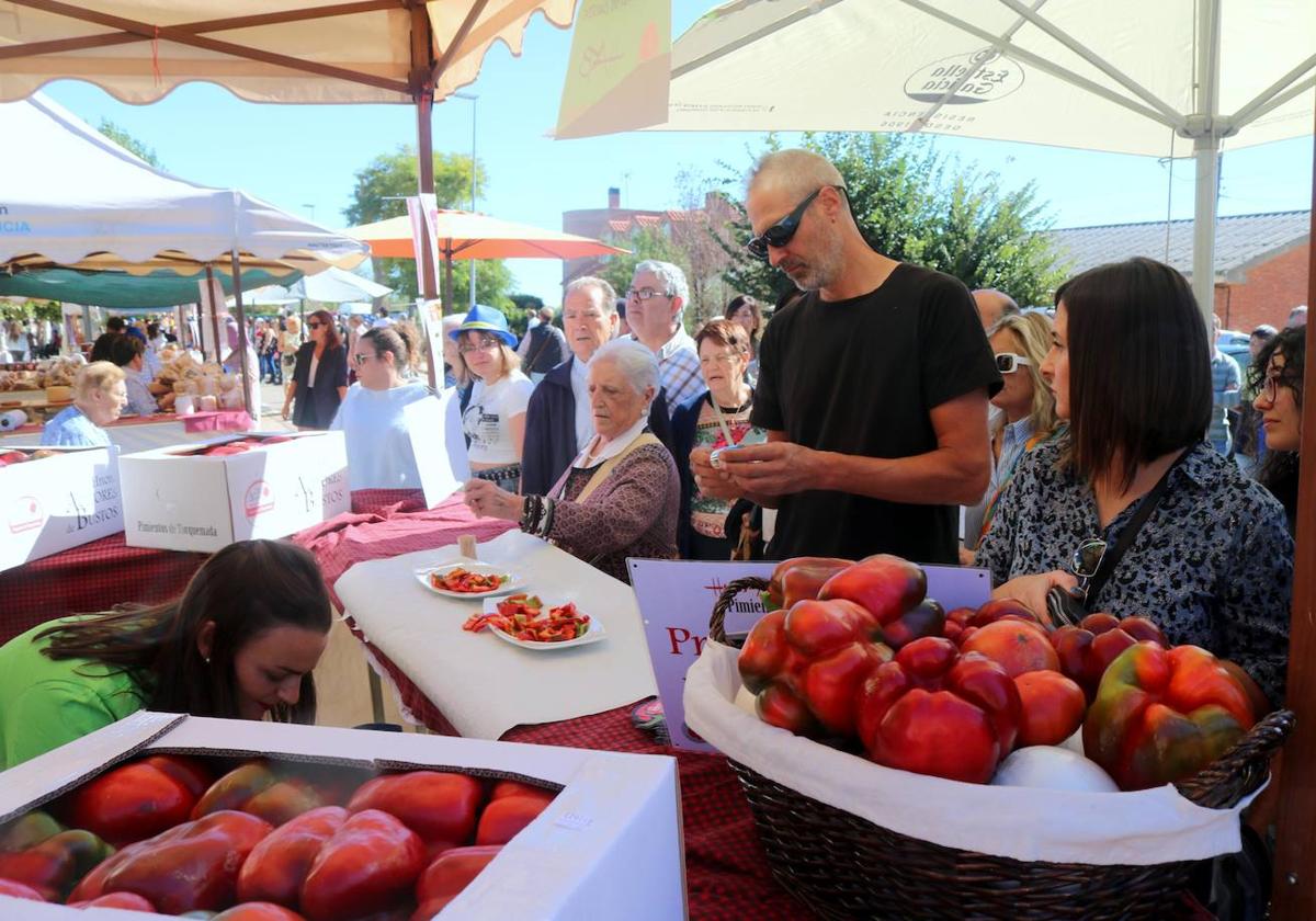 Numerosas personas guardan turno para probar y comprar pimientos en la feria de Torquemada.