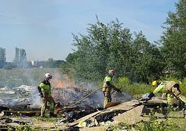 Los bomberos apagan un incendio anterior en la zona.