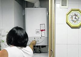 Una mujer conecta una caldera de calefacción en una vivienda.