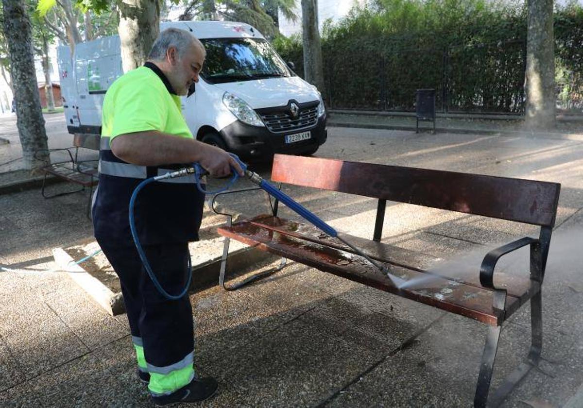 Un trabajador de la limpieza elimina la suciedad de un banco.