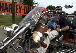 Un niño sujeta el manillar de una motocicleta Harley Davidson en Barcelona.