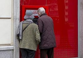 Dos personas sacan dinero de un cajero automático.