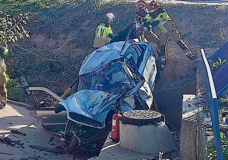 Los bomberos tratan de sacar al herido del interior del coche siniestrado.