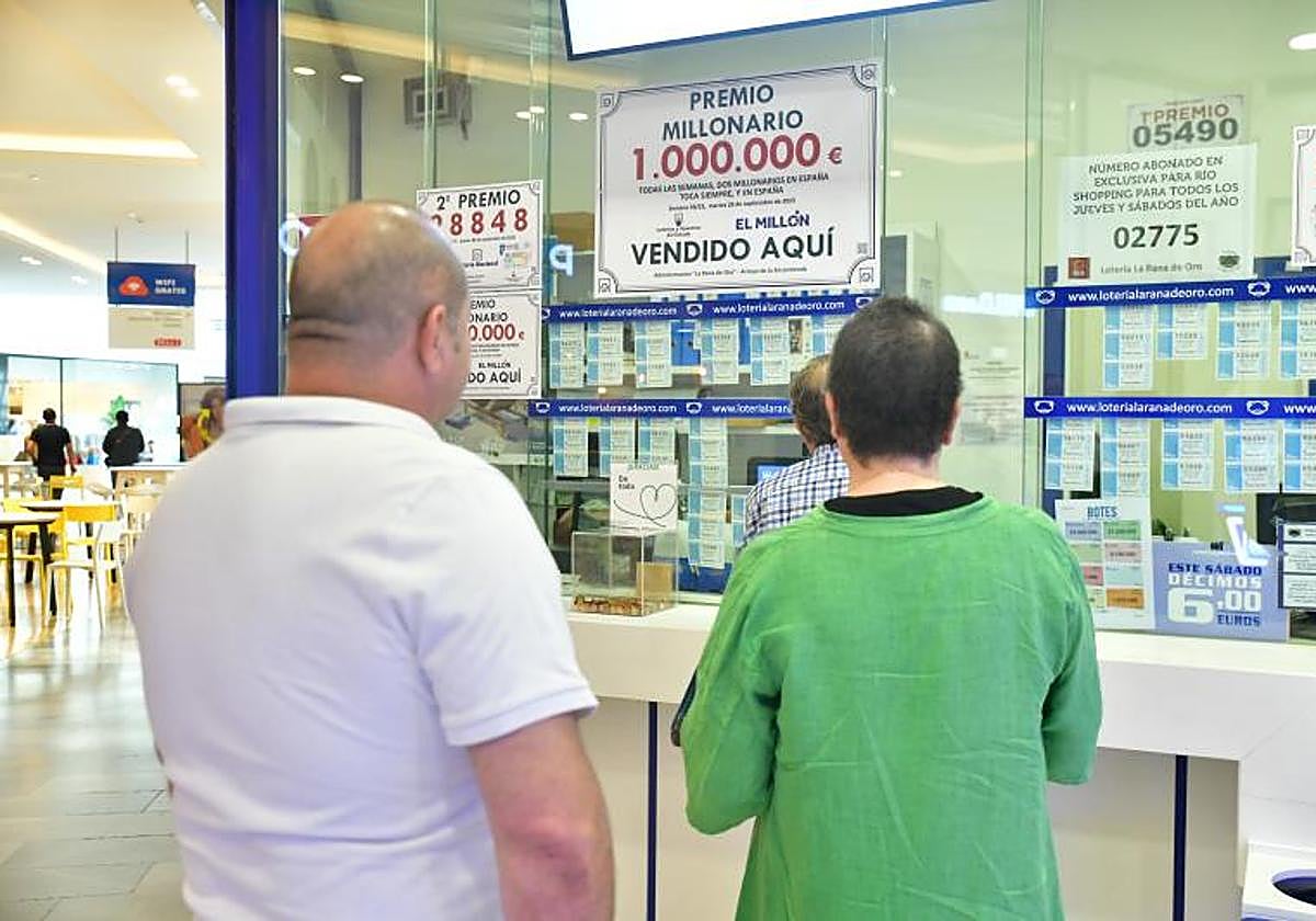 Dos personas esperan a la cola de una administración de lotería.