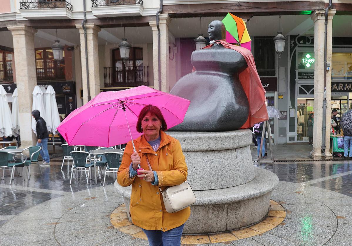 Paula González posa con un paraguas rosa delante de la estatua de la Mujer Palentina.