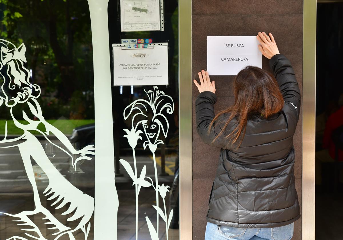 Una persona coloca un cartel en la puerta de un establecimiento de Valladolid.