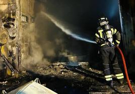 Un bombero trabaja en la extinción de las llamas en una zona de la fábrica Granalu.