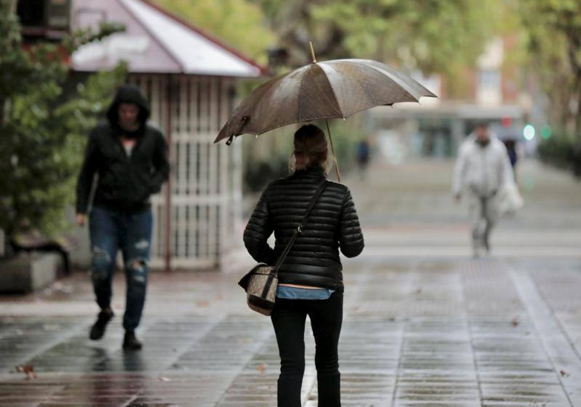 Una mujer se protege de la lluvia en Valladolid.