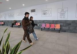 Dos jóvenes caminan por la zona de andenes, en cuyas paredes se ven las siluetas de San Bernardo, la ermita de San Juan, el Salón o Isla Dos Aguas.