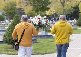 Dos hombres llevan un centro de flores por el Día de Todos los Santos en un cementerio de Valladolid, el año pasado.