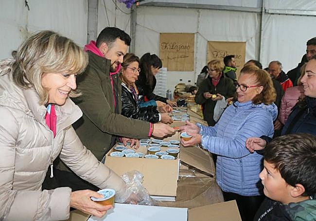 La alcaldesa, a la izquierda, reparte flanes de queso entre los vecinos.