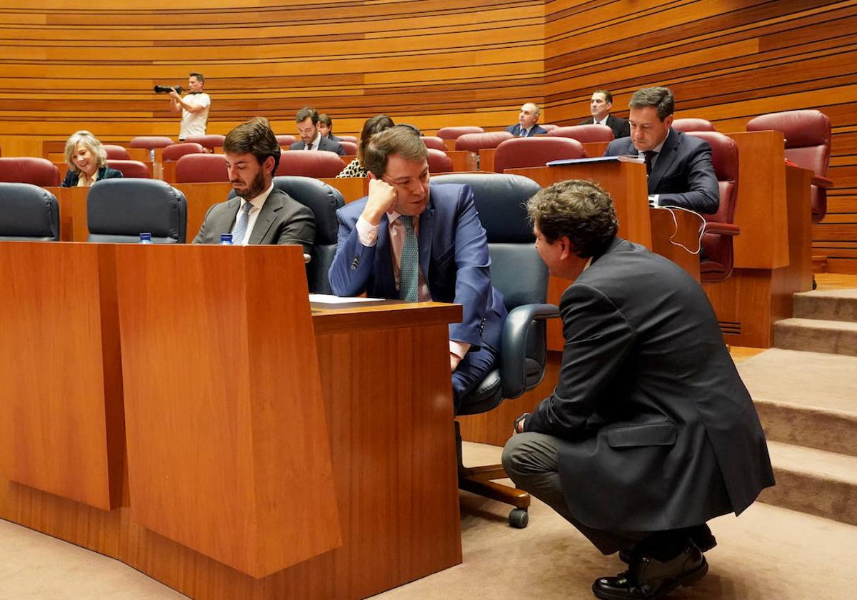 El presidente Mañueco habla con el consejero Fernández Carriedo en un pleno de las Cortes de Castilla y León.