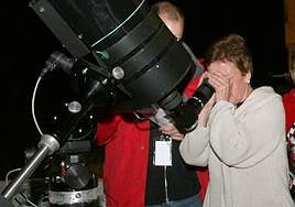 Una mujer mira el firmamento a través de un telescopio.