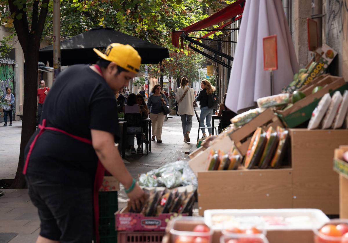 Un dependiente coloca fruta en un expositor exterior en una imagen de archivo.