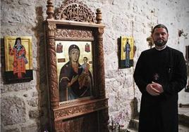 El padre ortodoxo Danut Mures posa frente a algunos iconos que permanecen fijos en la iglesia católica de Villatoro.