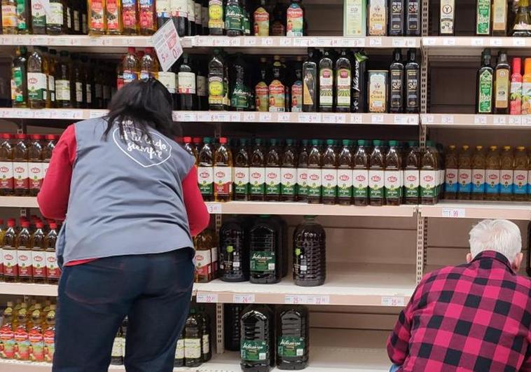 Un cliente y una empleada en el pasillo del aceite de un supermercado.