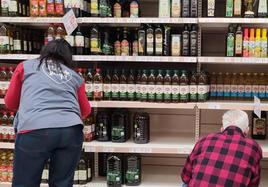 Un cliente y una empleada en el pasillo del aceite de un supermercado.