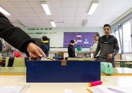 Una alumna deposita su teléfono móvil en una caja antes del comienzo de una clase.