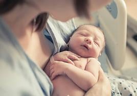 Un recién nacidos en brazos de un familiar.