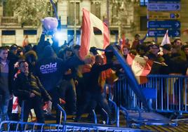 Varios jóvenes destrozan las vallas de seguridad que les separan de la policía, durante una manifestación contra la amnistía frente a la sede del PSOE en Ferraz.