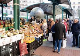 Varios clientes esperan a ser atendidos en uno de los puestos del mercado de la plaza de España.