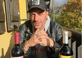 Gabriel de la Rosa posa con dos botellas de vino con la imagen del grupo Shinova