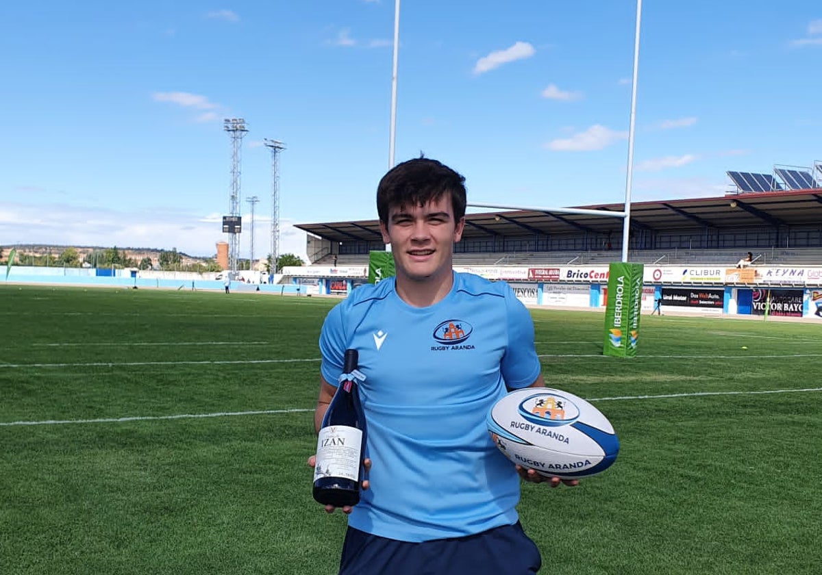 Juan Calvo posa en un campo de rugby con una botella de vino y un balón