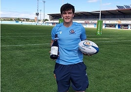 Juan Calvo posa en un campo de rugby con una botella de vino y un balón